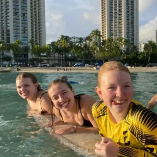 3 piger ligger på et surfboard på Waikiki Hawii på højskole i udlandet