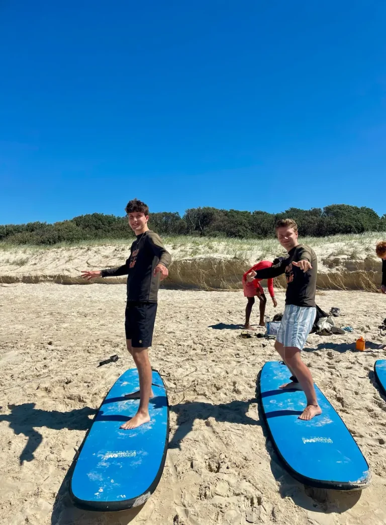 To elever står på surfboards på stranden i Australien på højskole i udlandet