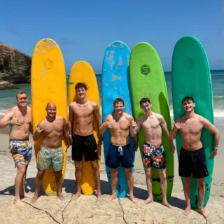 6 gutter med deres surfboards poserer på stranden inden de skal surfe på højskole i udlandet