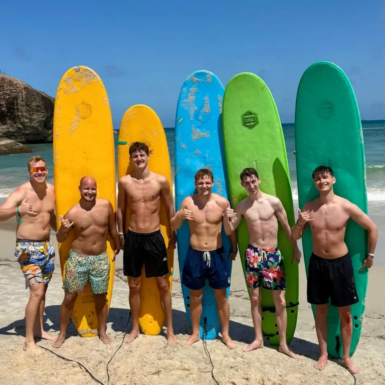 6 gutter med deres surfboards poserer på stranden inden de skal surfe på højskole i udlandet