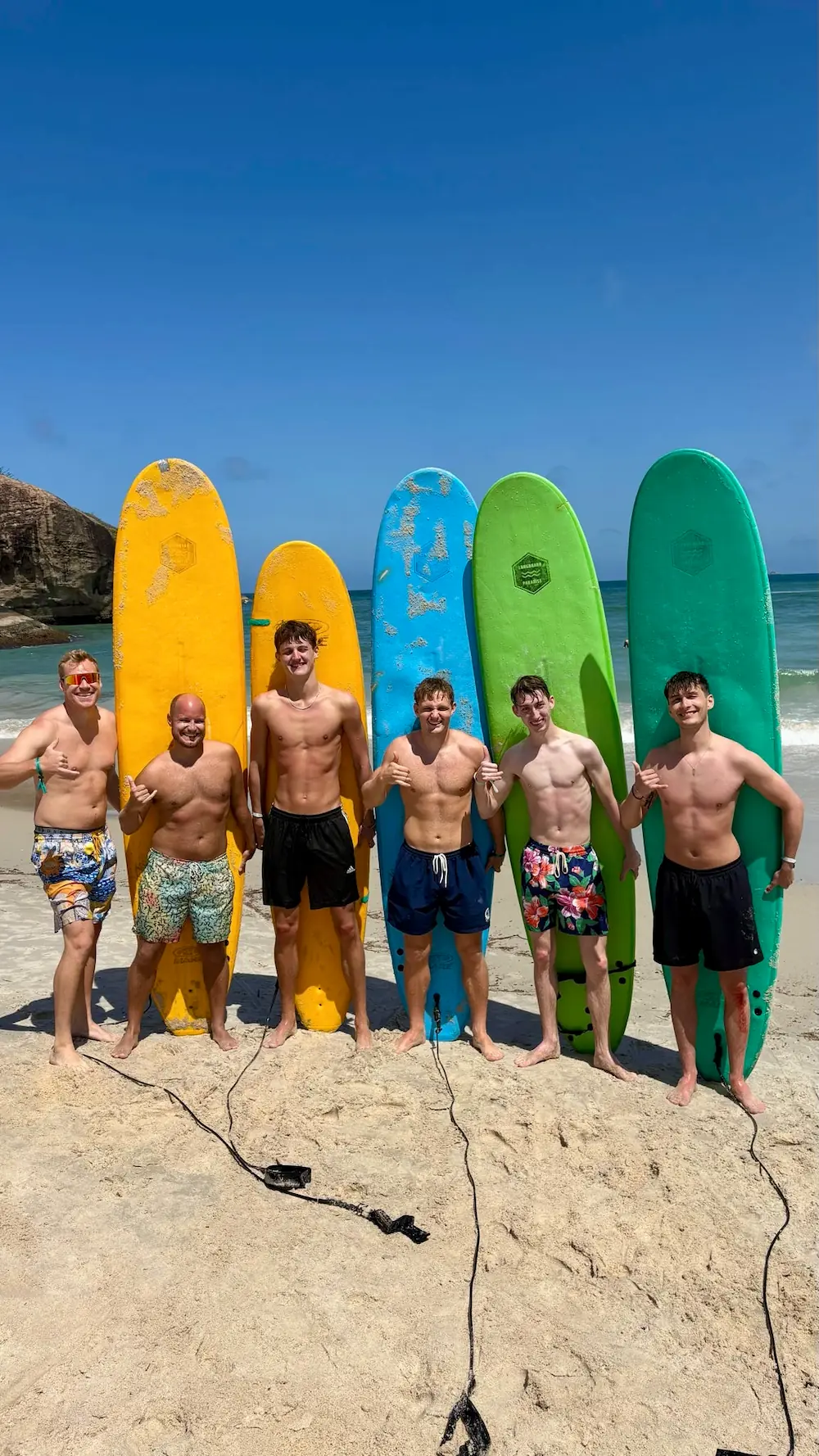 6 gutter med deres surfboards poserer på stranden inden de skal surfe på højskole i udlandet