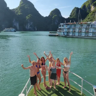 Elever på fronten af båd vinker til kamerat i Ha long bay på højskole i udlandet