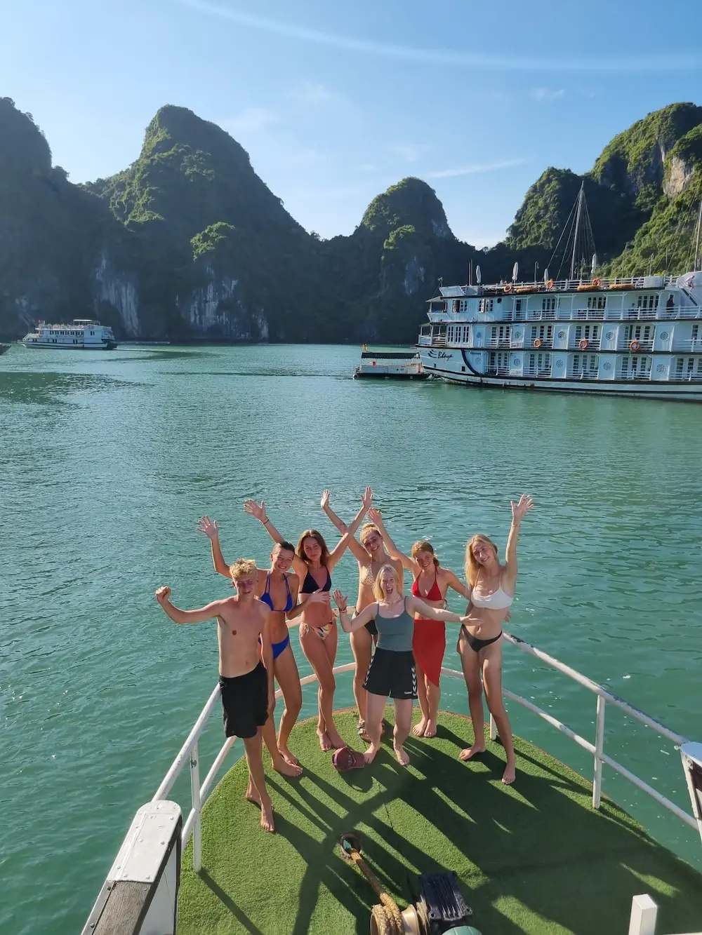 Elever på fronten af båd vinker til kamerat i Ha long bay på højskole i udlandet