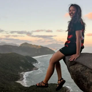 Elev sidder på kanten af en klippe med udsigt udover strande i Rio på højskole i udlandet