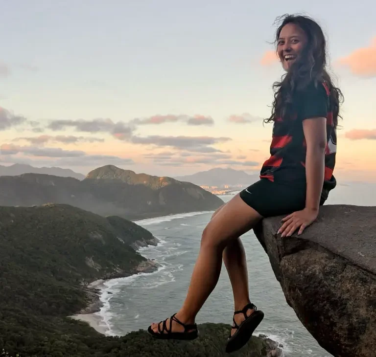 Elev sidder på kanten af en klippe med udsigt udover strande i Rio på højskole i udlandet